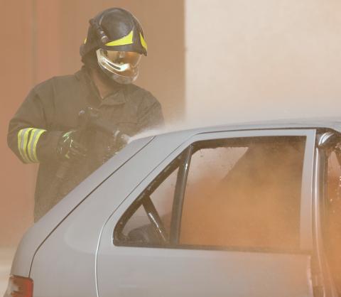 Feuerwehrmann löscht ein brennendes Auto